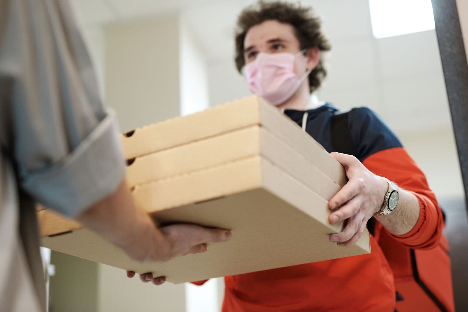 A courier handing sealed delivery boxes to a shop